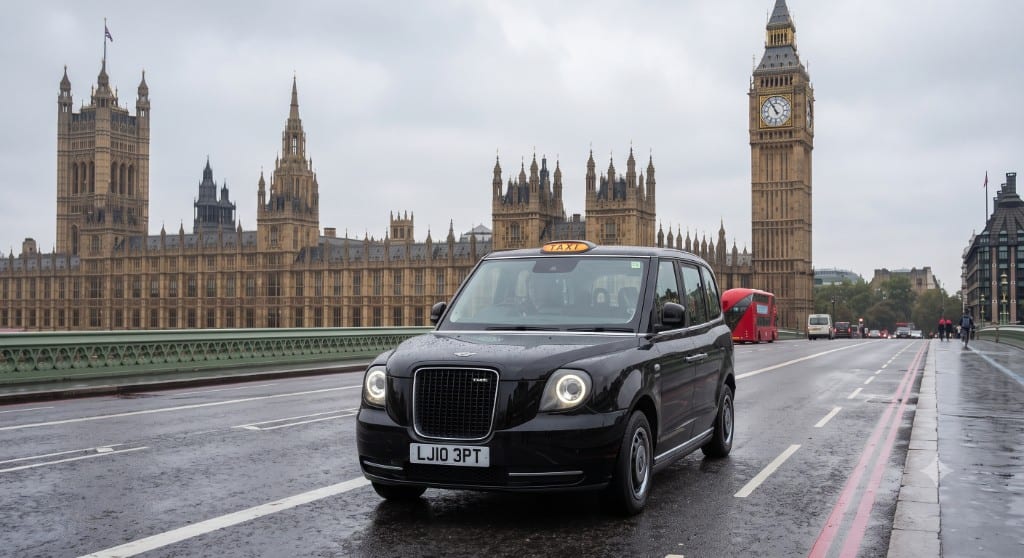 London black cab on Westminster Bridge in front of Big Ben and the Houses of Parliament — iconic UK taxi service