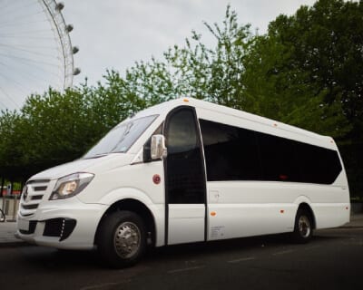 White 24-seater midi coach by the London Eye — UK midi coach hire